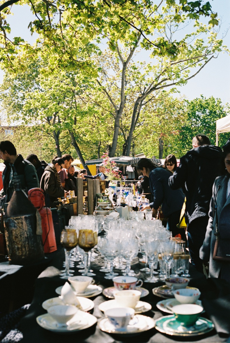 Trödelmarkt-Atmosphäre mit Geschirr und Glas im Tageslicht.